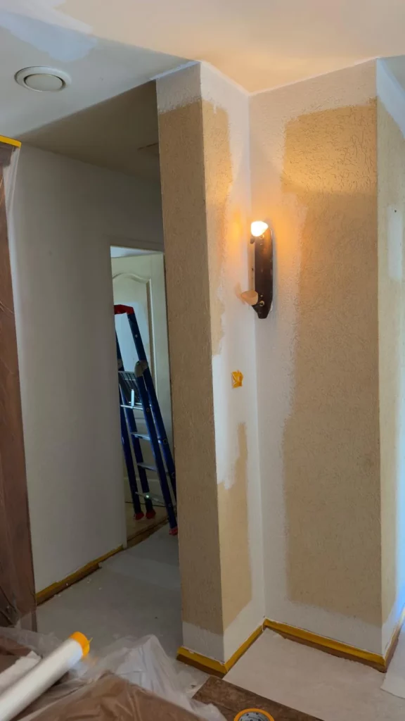 Mur enduit autour d’une porte avant peinture, avec protections au sol.
